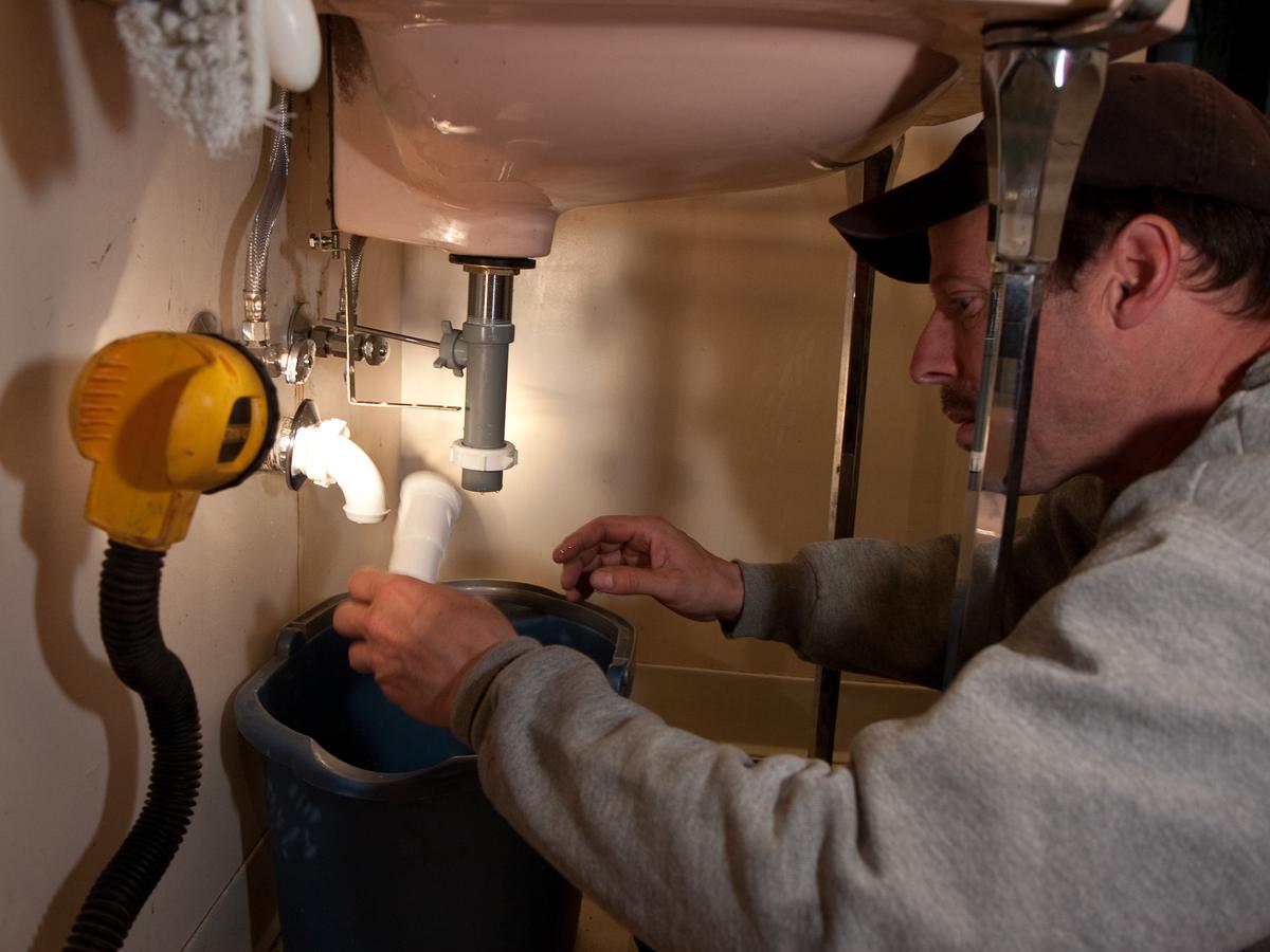 Plumber working on the drain pipe under a bathroom sink