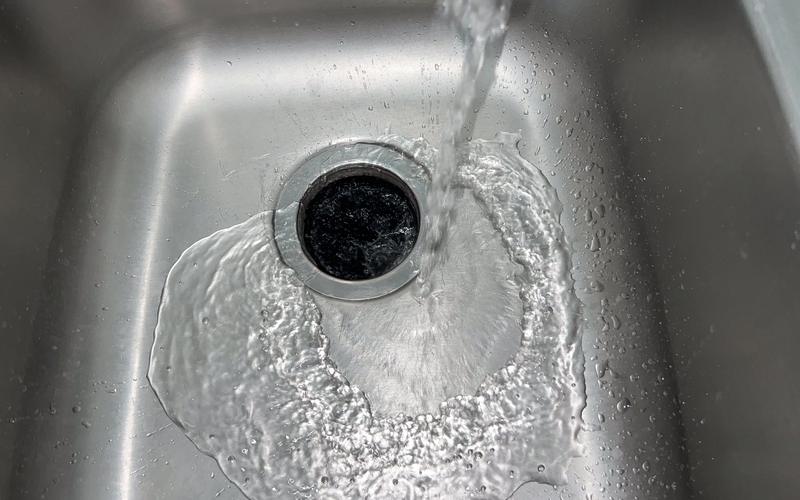 Water swirling down a stainless steel kitchen sink drain